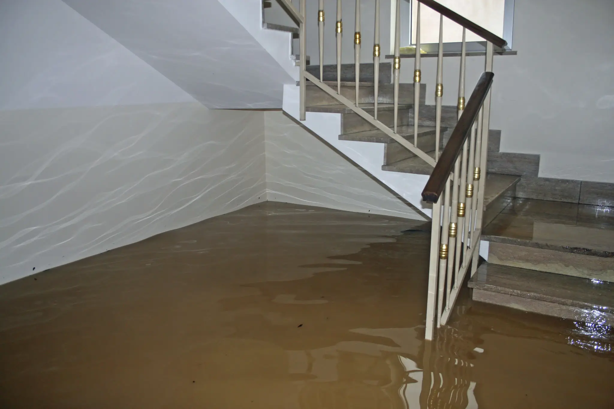 Flooded indoor area with water reaching stair railings.