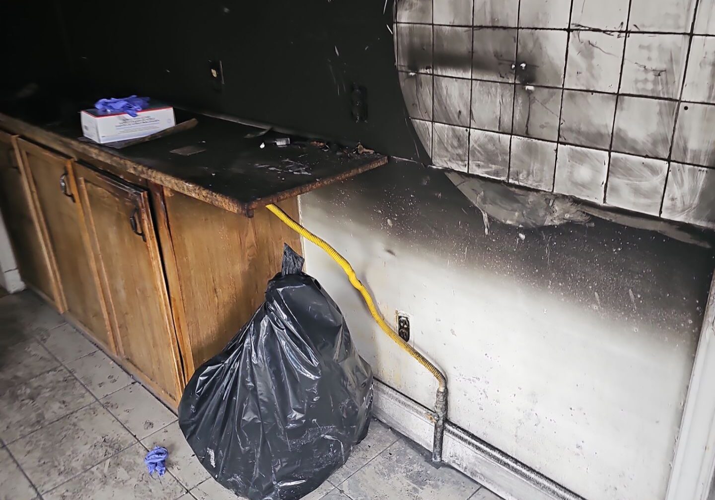 Fire-damaged interior with burnt wall and debris on the floor.