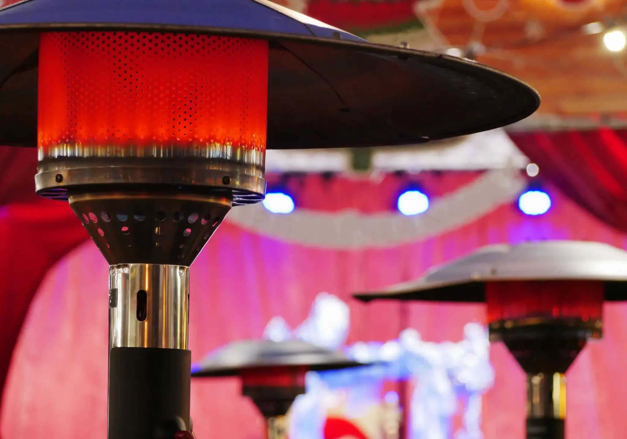 Heaters glowing warmly in an outdoor setting with decorative lights.